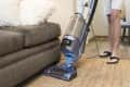 Legs of Caucasian man vacuuming rug near sofa