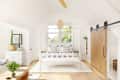 Bright bedroom with a white canopy bed, striped pillows, wooden sliding door, and potted plants on a dresser.