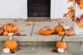 Pumpkins and autumn leaves on a porch with a bowl of candy, decorated with orange foliage.