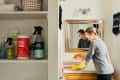 A women spraying the counters in her bathroom with cleaning spray while wearing rubber gloves