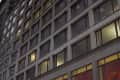 Generic exterior evening time establishing shot outside office or apartment building with large windows and lights illuminating rooms inside. Setting for any large city urban loft highrise in USA