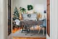 Dining room with Christmas tree, decorated mantel, and table set for a festive meal, viewed through open French doors.