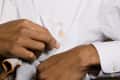 man using a gray towel to blot a brown-colored stain on a white button-up shirt