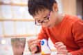 Young asian boy painting craft by color brush in classroom at school