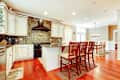 Luxury white kitchen with cherry hardwood and island with chairs.