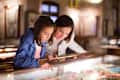 Cheerful mom and daughter looking at medieval expositions in museum