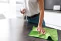 Close up of a young woman cleaning kitchen with detergent.