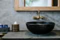 Black sink, vintage copper faucet, gray wall, mirror, loft bathroom interior details. Close up, minimalism concept