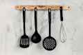 Black kitchen utensils against the background of a light texture wall. Kitchen wallpapers