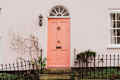 Light Pink or peach color front door and walls of the traditional English house.