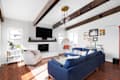 ELMHURST, IL, USA - SEPTEMBER 2, 2020: A renovated modern farmhouse living room with a blue couch, white fireplace, wood beams on a white shiplap ceiling, and a television mounted above the fireplace.