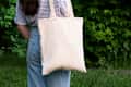 Empty reusable canvas tote bag mockup. Natural canvas eco-friendly shopper bag on girl's shoulder. Mockup for presentation of design or brand