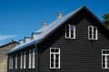 black wooden house under a gray roof against a blue sky. building architecture.