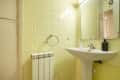 Bathroom with white wooden cabinets, glass-enclosed shower and square mirror above sink in vacation rental apartment