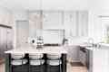 A luxurious kitchen with a large island, gold faucet and sputnik chandelier, stainless steel appliances, and white marble countertops.