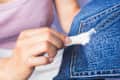 A young woman cleans gum from her jeans. How to remove stains