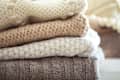 Stack of cozy knitted sweaters on a wooden table. Retro style. Warm concept