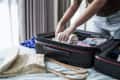 Woman packing suitcase at home preparing to summer travel trip