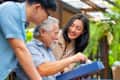 Asian adult couple surprised elderly father with gift box at outdoor cafe restaurant on summer holiday vacation.
