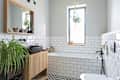 Modern bathroom in industrial design in stylish interior. White tiles, wooden cabinet and mirror and bathroom sink in black colour in new apartment.