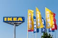 Bratislava, Slovakia - 06102025: IKEA logo and flags against a blue sky in Bratislava, Slovakia. Brand colors yellow and blue.