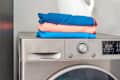 Stack of clean sports towels neatly folded on a modern washing machine in a bright laundry room. Concept of fitness hygiene, active lifestyle, and home care routine