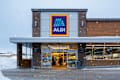New Hartford, NY - Jan 2, 2026: Close-up view of Aldi Market, which stands for Albrecht Discount during active snowfall. ALDI is a Global Discount Supermarket Chain that Originated in Germany