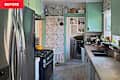 Narrow kitchen with stainless steel appliances, floral wallpaper, wooden countertops, and a sink with plants.