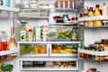 Refrigerator filled with various foods including fruits, vegetables, yogurt, drinks, and condiments.