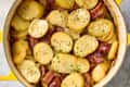Sliced potatoes, sausage, and bacon in a yellow pot, garnished with parsley and simmering in broth.