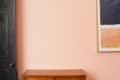 Black door, peach wall, abstract art with dark and light rectangles, and a wooden cabinet.