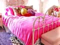 Colorful bedroom with lots of pink and lavender accents. One wall with opalescent beads. Lots of colorful art, decor