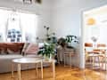 White living room with grey couch, wooden coffee table and plants in planters.