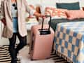 shot of someone rolling their pink suitcase out of their bedroom.