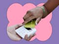 A hand holding a green credit card is tapping a white card reader, with another hand underneath.