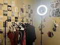 grid of black and white photos, clothing rack gold and black, ring light, posters on wall, reflective hexagons