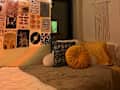 green and white bedding, gallery wall of posters, macrame hanging above bed, various throw pillows orange and yellow, disco ball with rainbow lighting