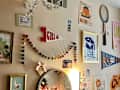 Colorful wall decor featuring a mirror, framed art, and a pennant, with a variety of personal items on a dresser.