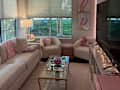 Cozy living room with a light pink sofa, two armchairs, a glass coffee table, and decorative art on the walls.