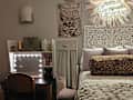 Cozy bedroom featuring a leopard print bolster pillow, decorative pillows, a vanity with lights, and a wall art of a leopard.
