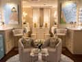 Chic lounge area with two curved chairs, a glass table, and floral decor, surrounded by stylish artwork and lighting.