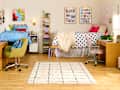 Colorful shared bedroom with two beds, a polka dot comforter, desks, and a patterned rug.