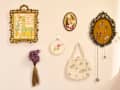 Framed vintage artwork titled "A Floral Fantasy in an Old English Garden," decorative embroidery, a small purse, and dried flowers on a wall.