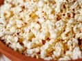 Popcorn in a wooden bowl, close-up view showing fluffy kernels.