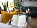 POV of young woman relaxing at home reading a book lying on sofa. Lifesyle concept.
