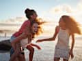 Young women piggybacking on sandy beach