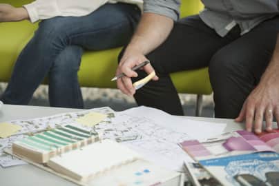 Two people reviewing architectural plans and color swatches on a table.