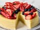 Ricotta cheesecake topped with berries with a slice cut out