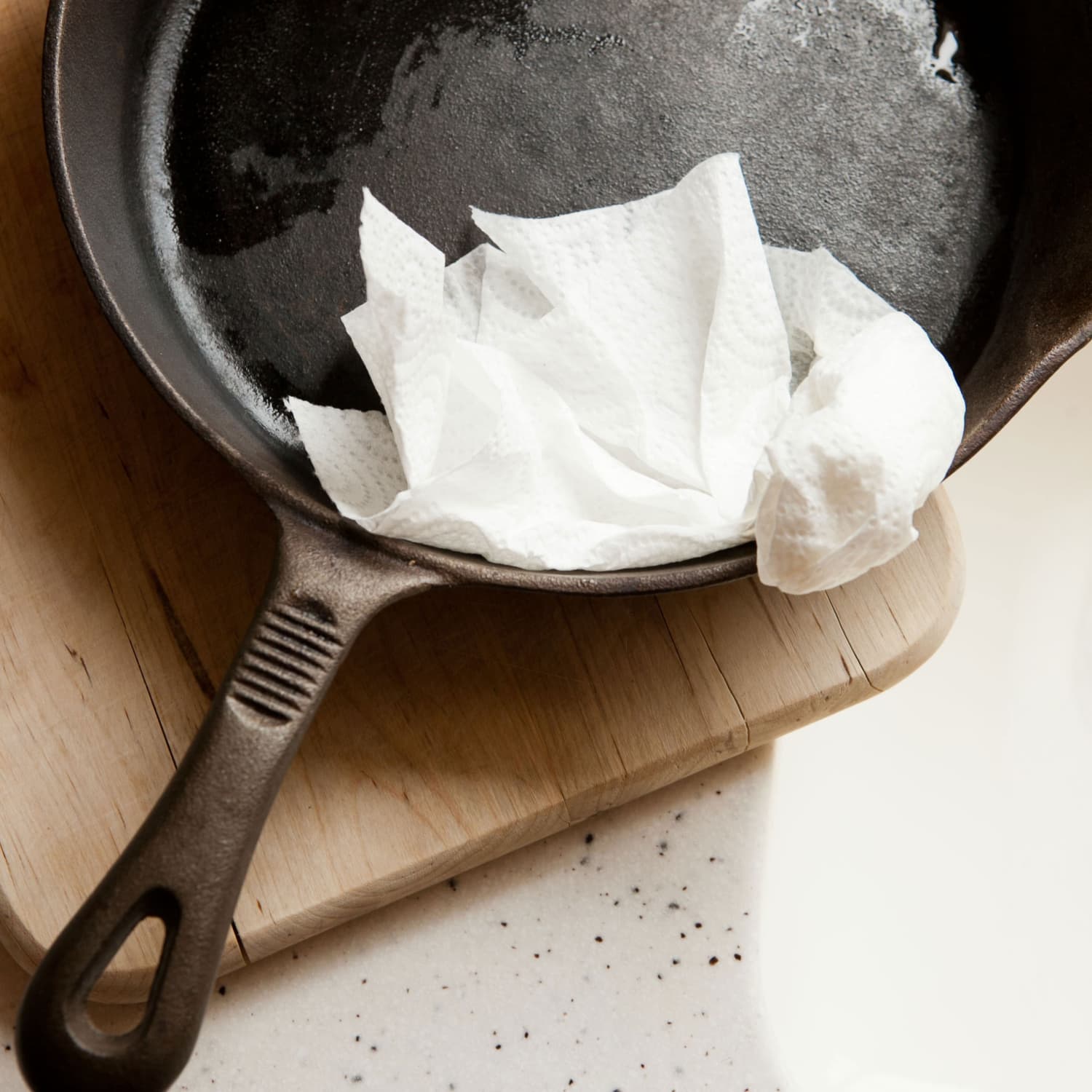 Dirty cast iron skillet being prepared for cleaning with coarse salt, brush,  scraper and dish towel on a counter Stock Photo - Alamy