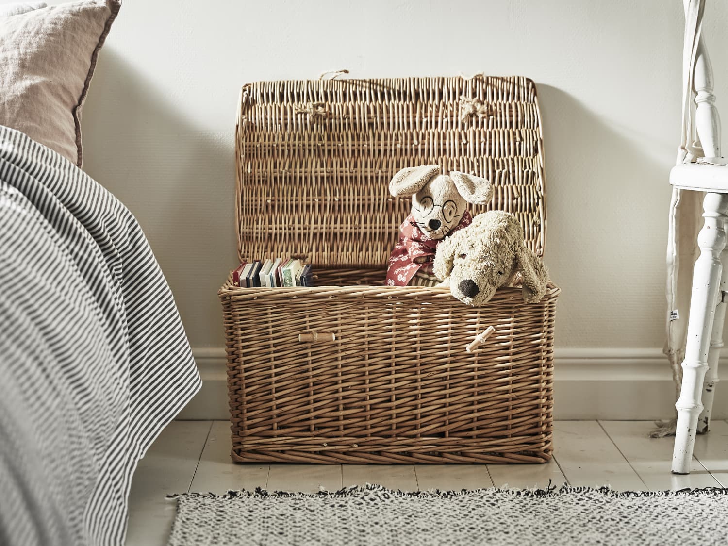 baby covered with pink blanket in brown woven basket with brown